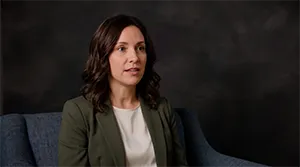 Example video shoot frame: a woman in a green blazer seated in front of a dark canvas backdrop